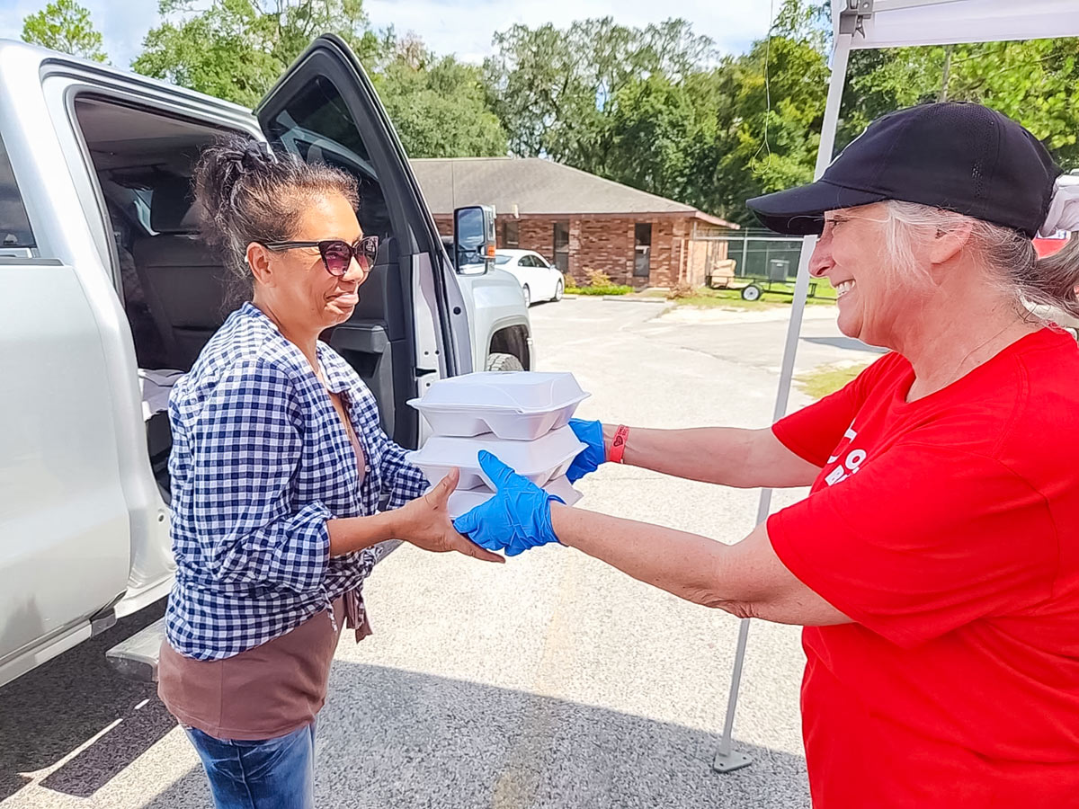 Volunteer handing boxes of food to woman